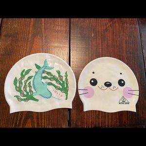 Two silicone swim caps, Narwhal and seal designs.
